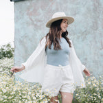 sky blue bev tank with white oversized button up shirt and linen white shorts and hat