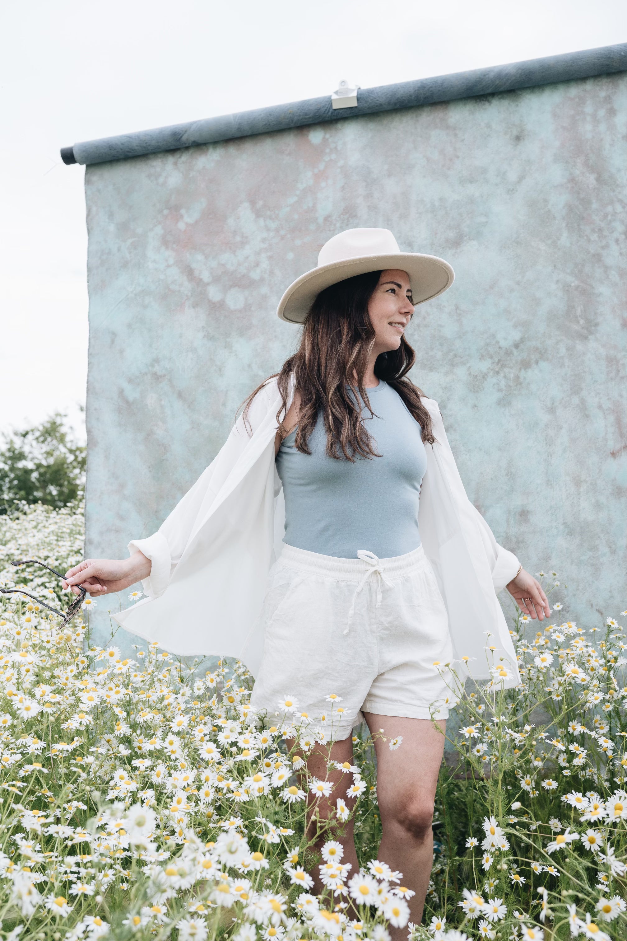 sky blue bev tank with white oversized button up shirt and linen white shorts and hat