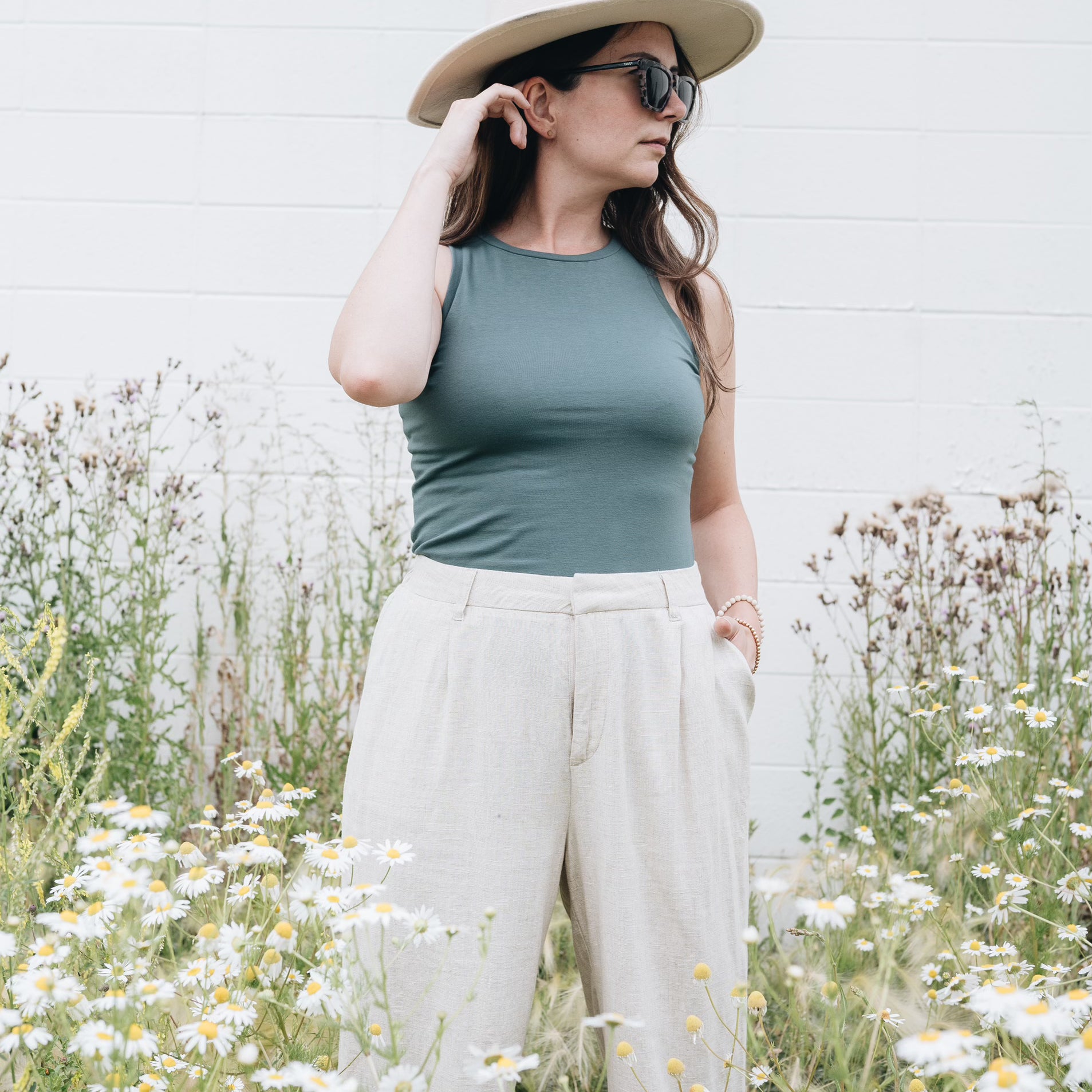 Teal high neck tank top with hat and subglasses and wide leg pants