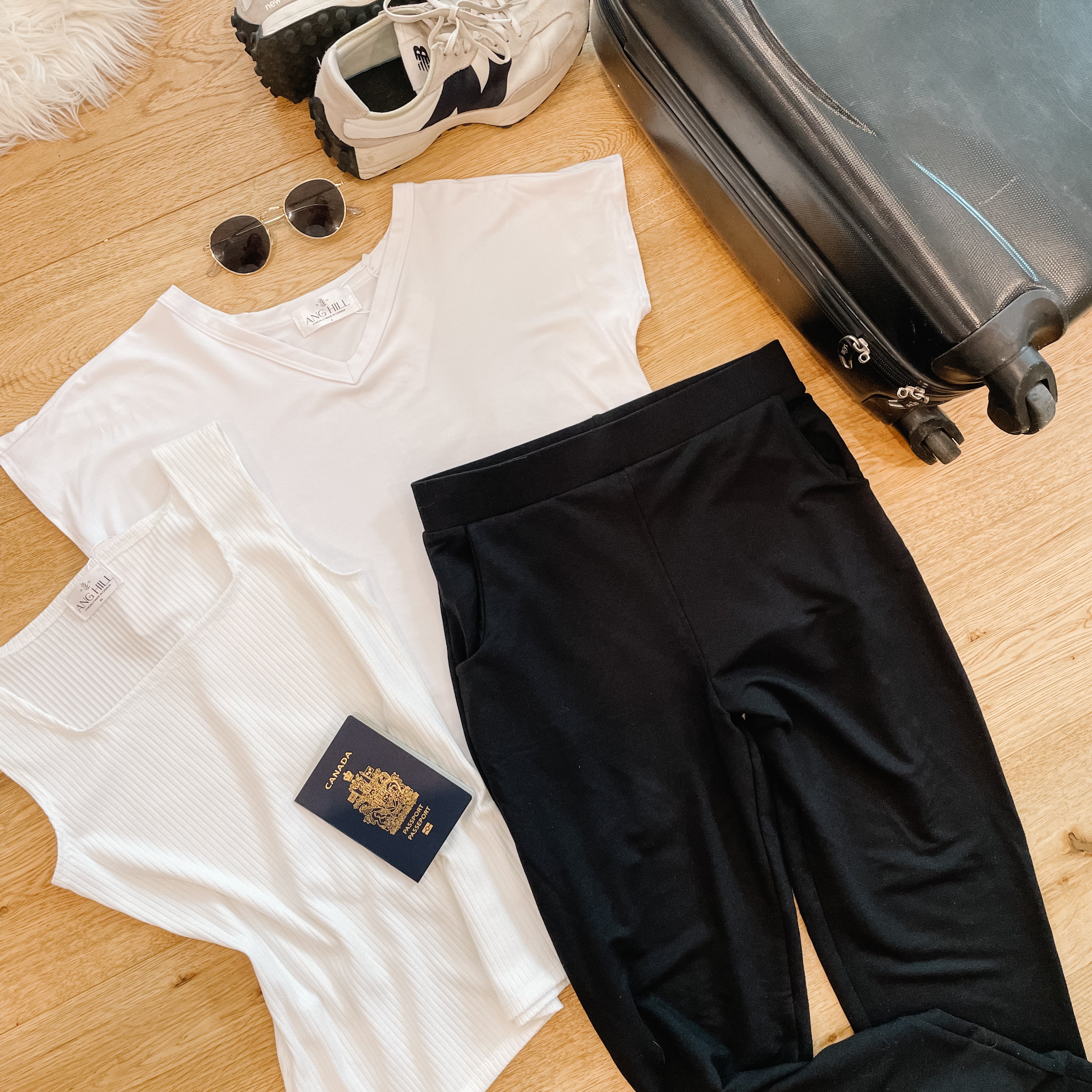 flatlay of travel capsule wardrobe with white t-shirt cream tank and black skinny joggers