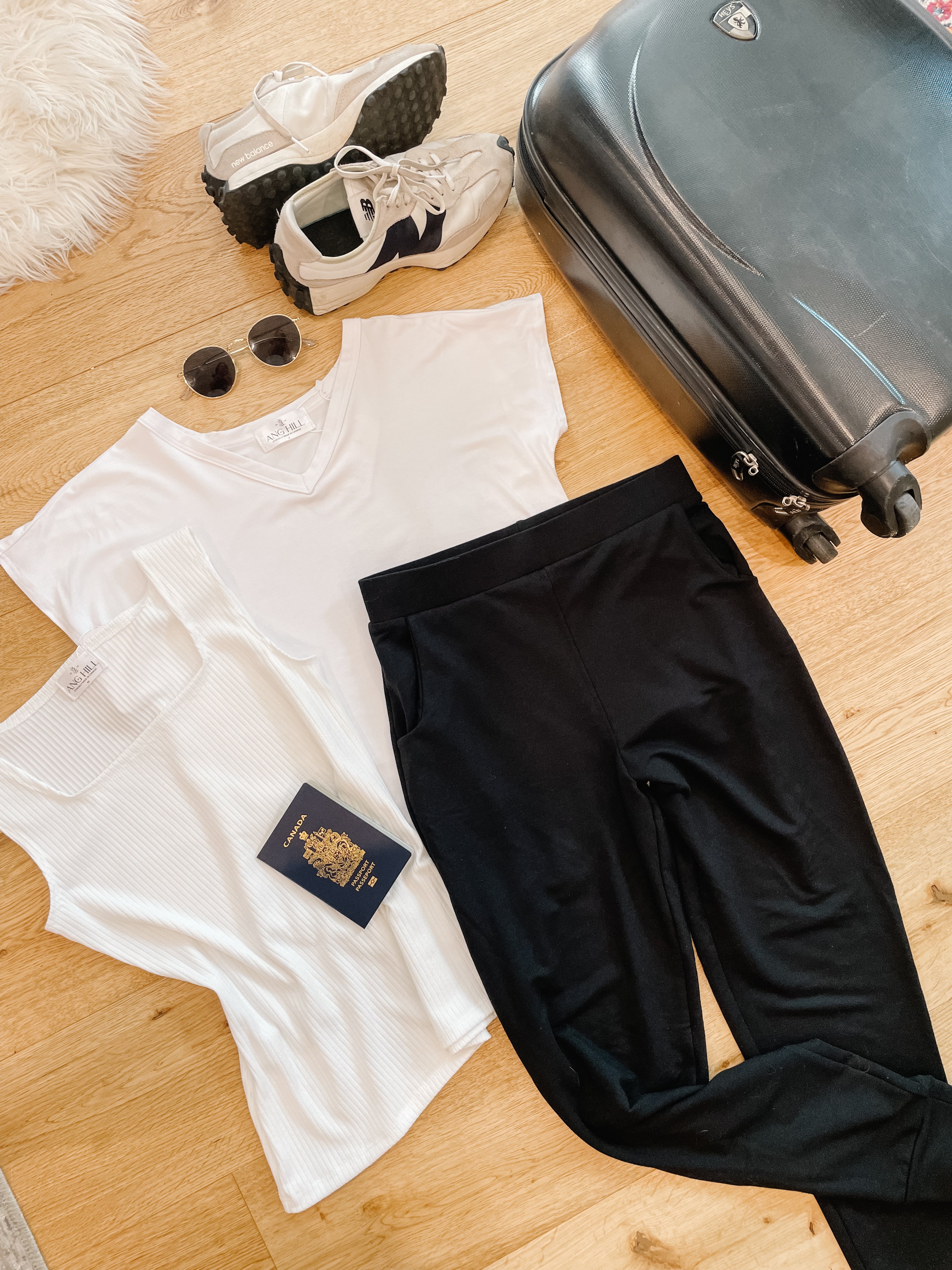 flatlay of travel capsule wardrobe with white t-shirt cream tank and black skinny joggers