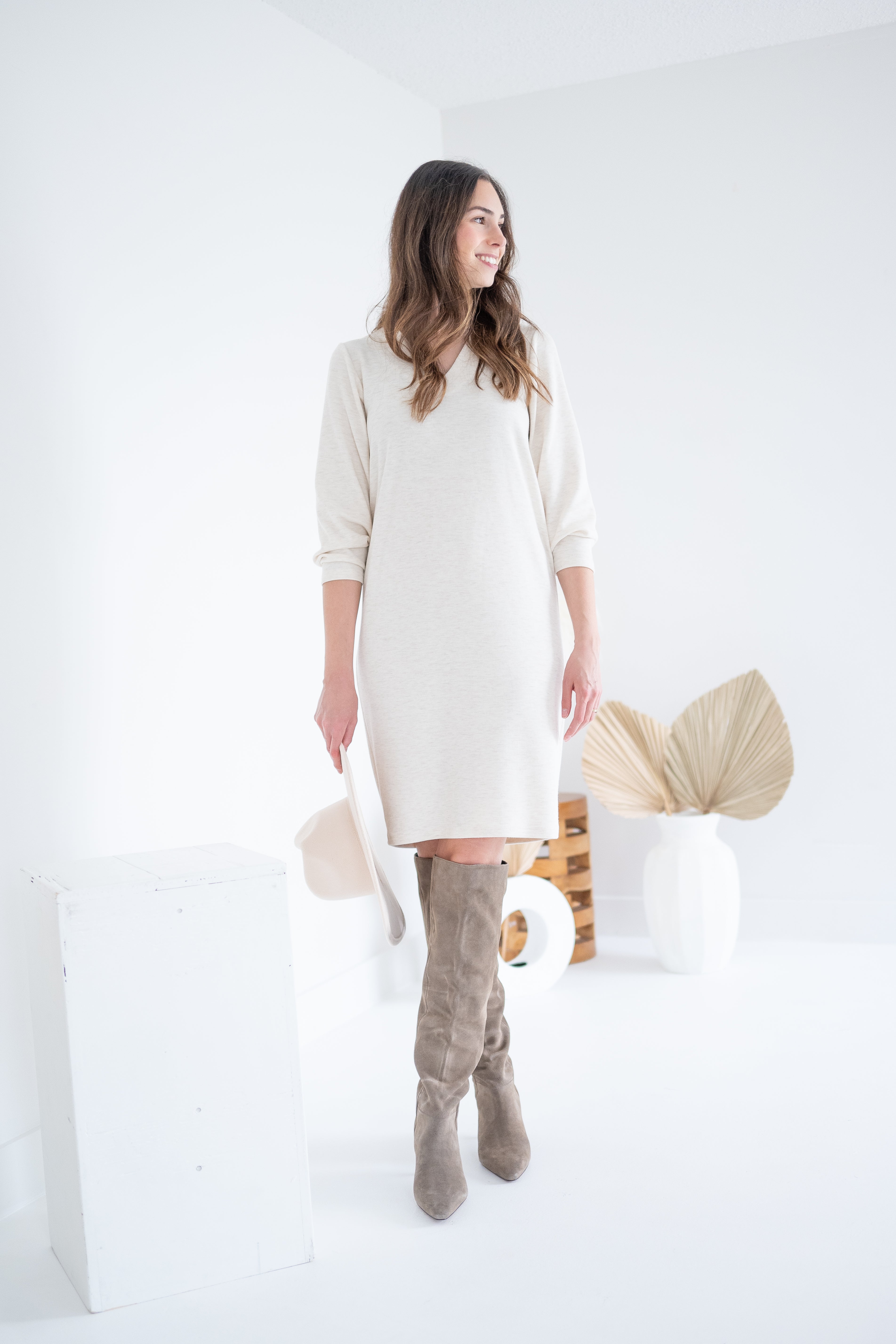 cream sweater dress with knee high boots and hat