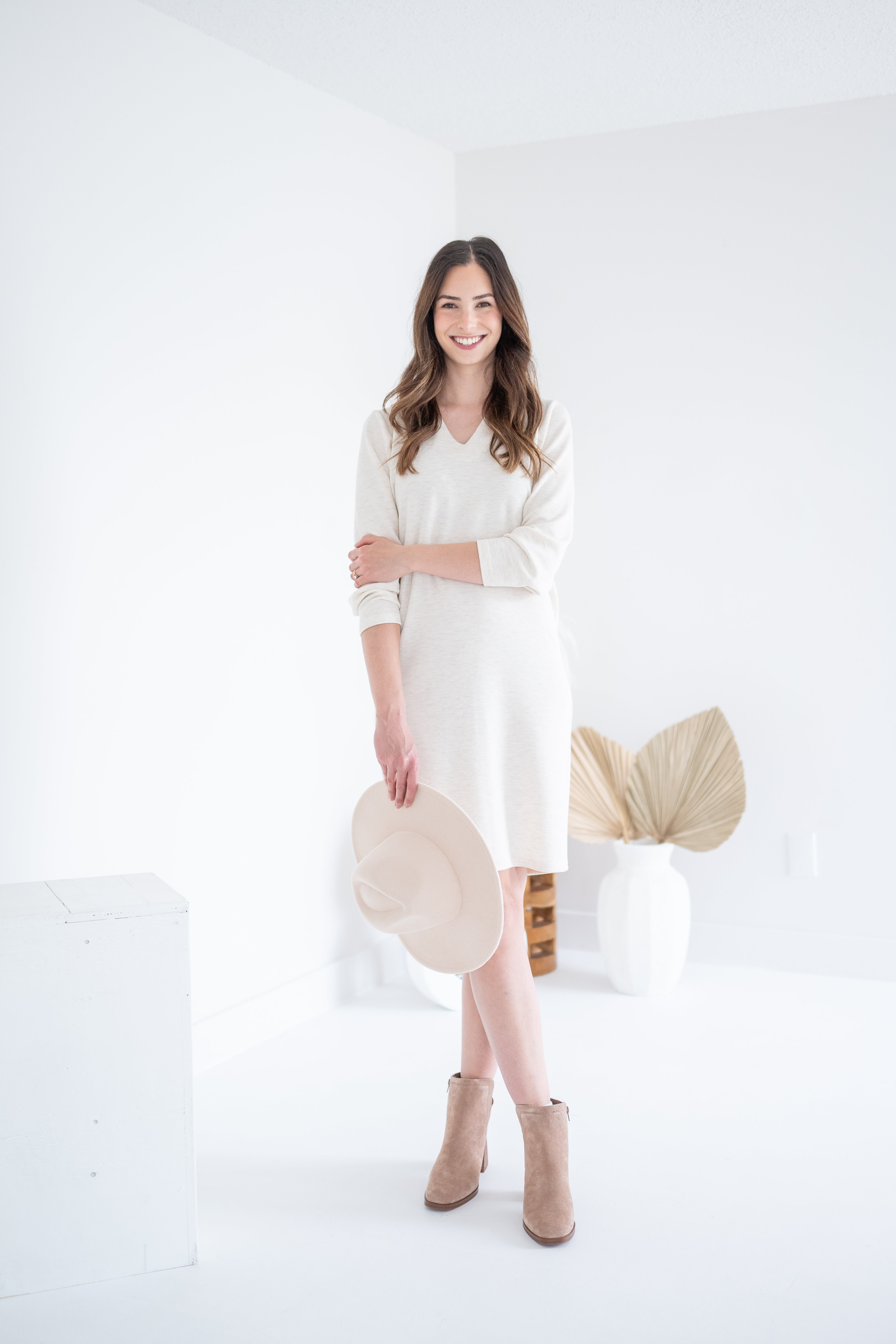 woman wearing cream vneck long sleeved dress with beige hat and beige booties