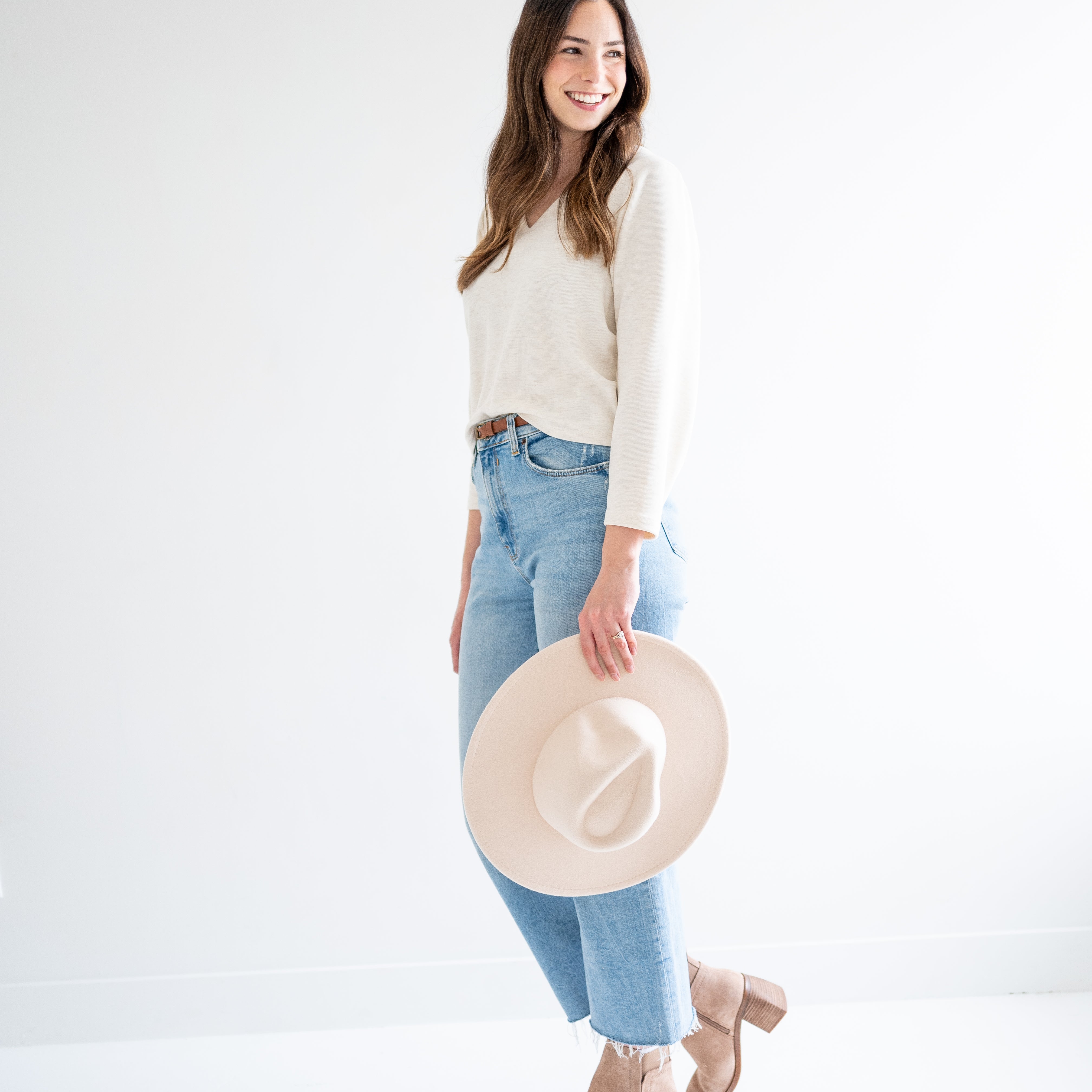 woman wearing cream cropped sweater, jeans and a beige wide brim hat