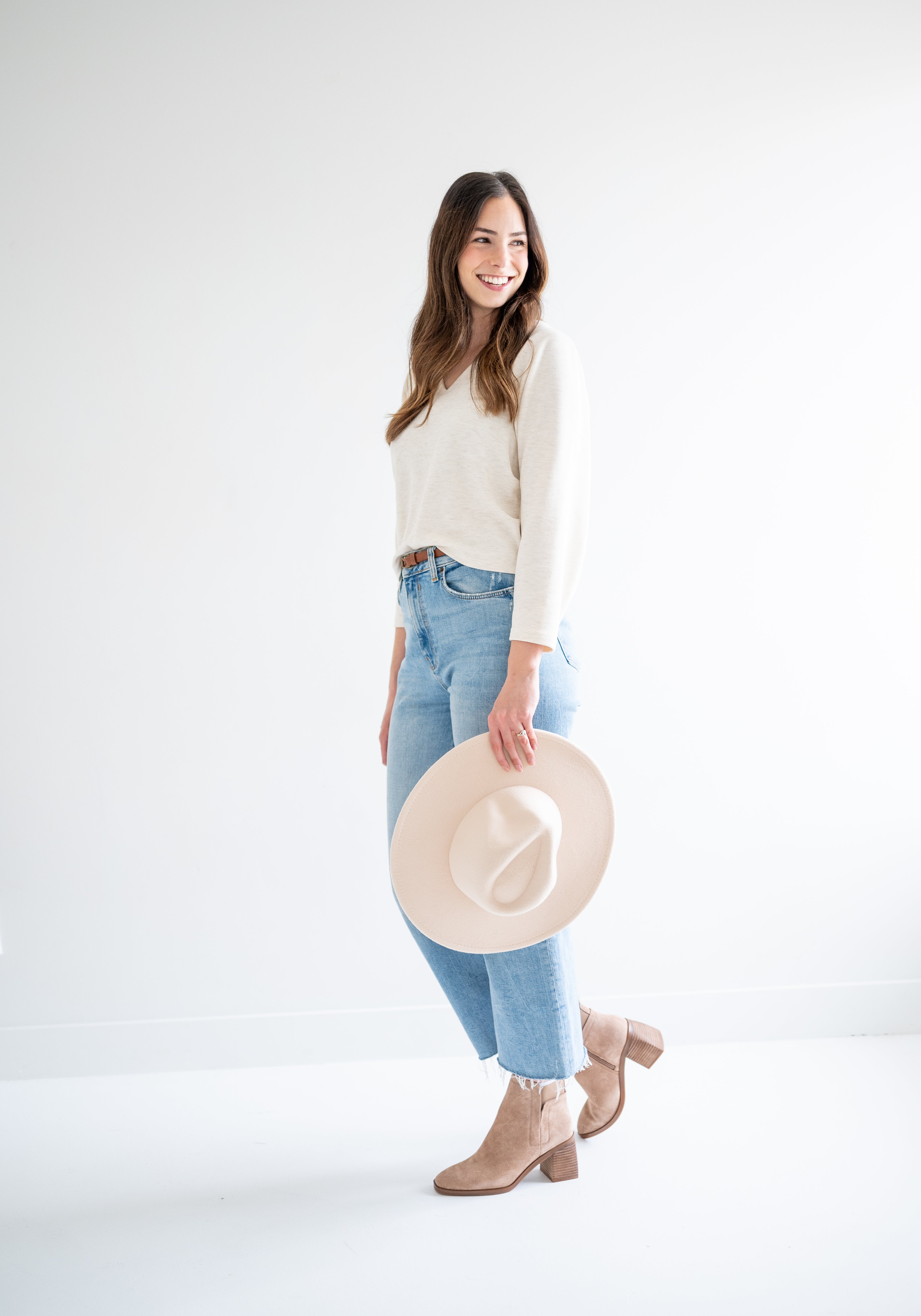 woman wearing cream cropped sweater, jeans and a beige wide brim hat