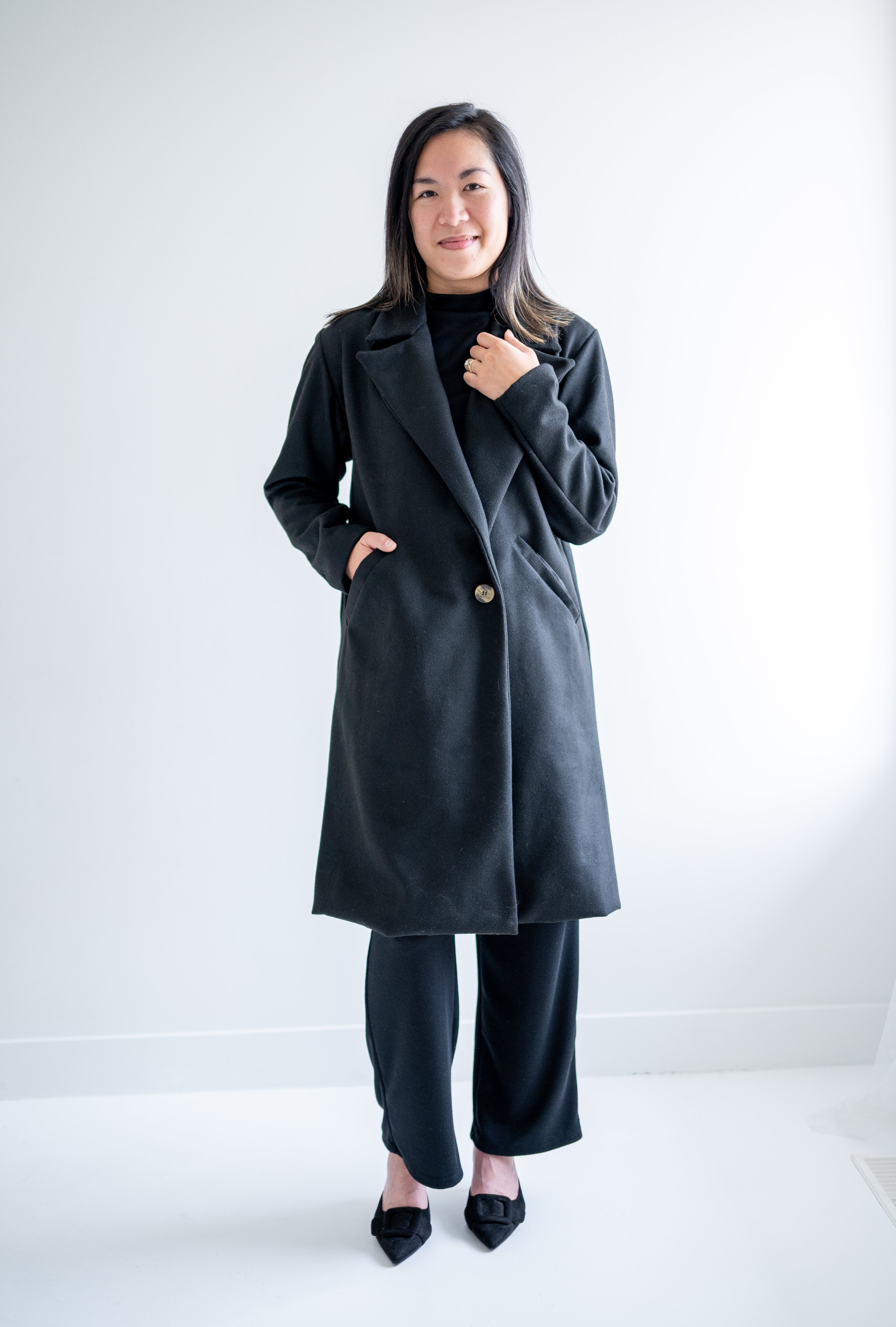 front view Black wool coat with one button. Wide collar knee length. Made in canada.