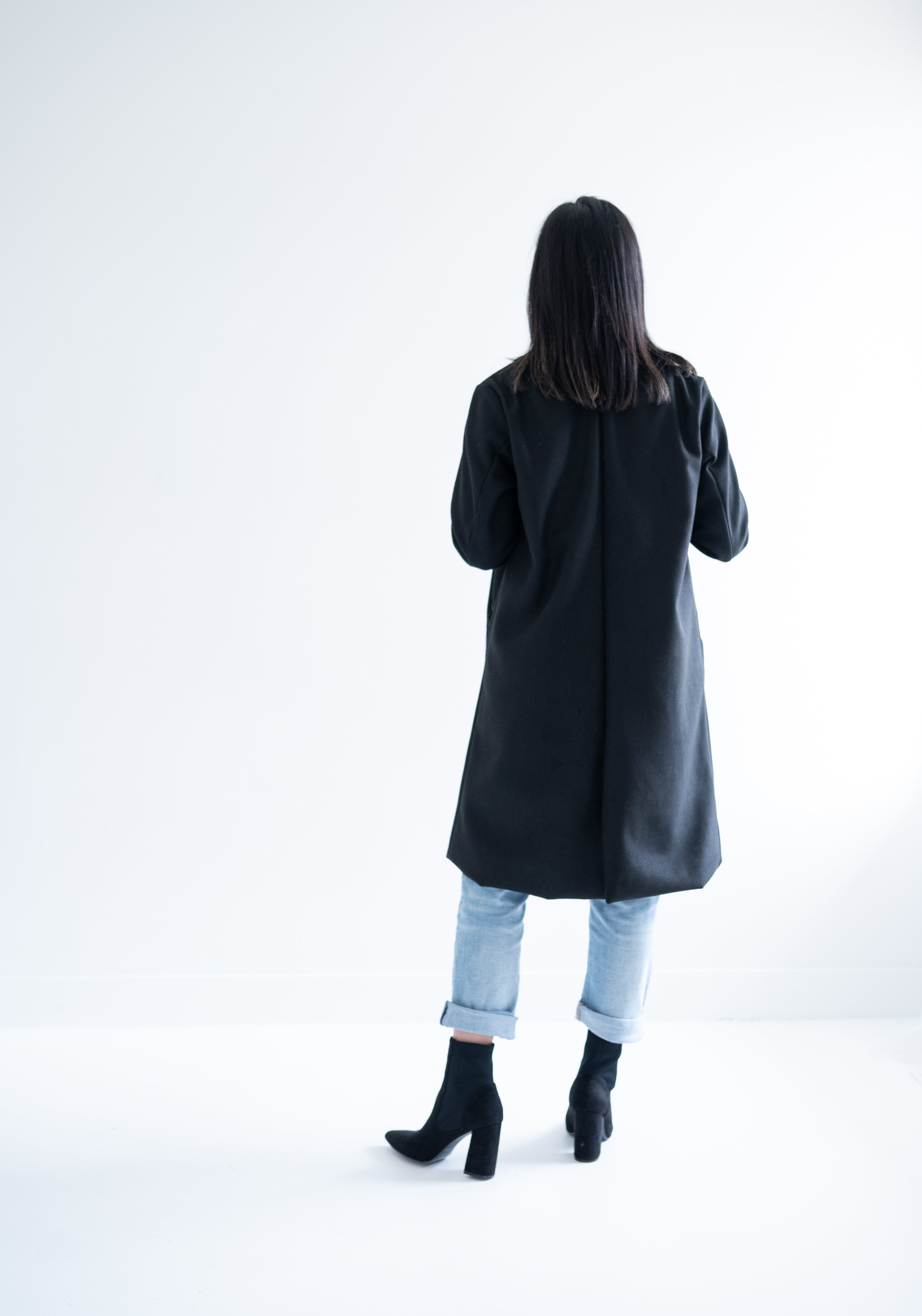 back view of woman wearing black knee length wool coat
