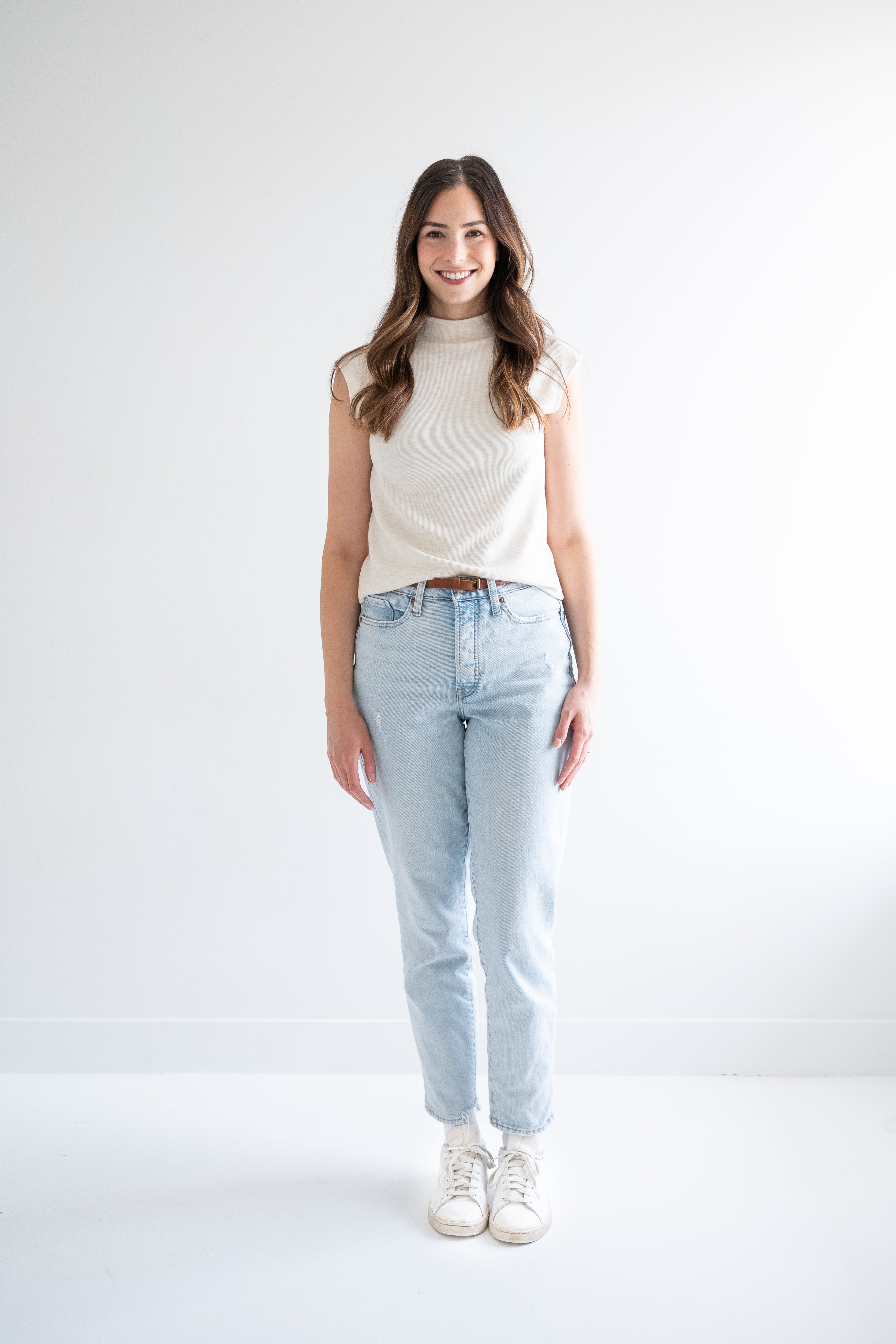 front view of woman wearing cream sleeveless mockneck sweater