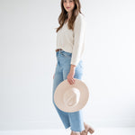 side view of cream v-neck sweater and beige fedora hat