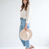 side view of cream v-neck sweater and beige fedora hat