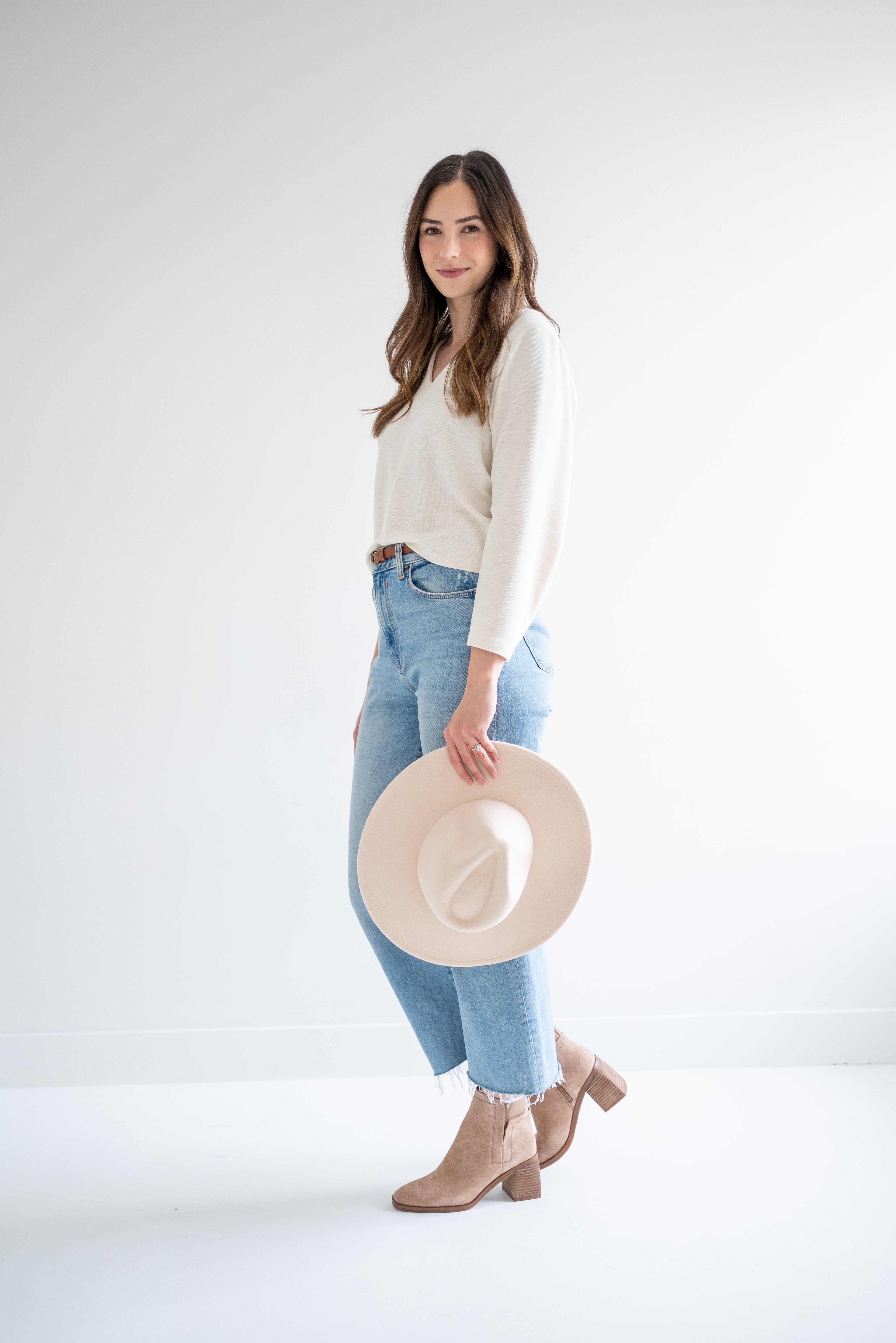 side view of cream v-neck sweater and beige fedora hat