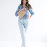 woman wearing blue v-neck sweater, fanny pack and light wash denim and sneakers