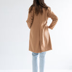 back view of camel wool coat with denim and sneakers