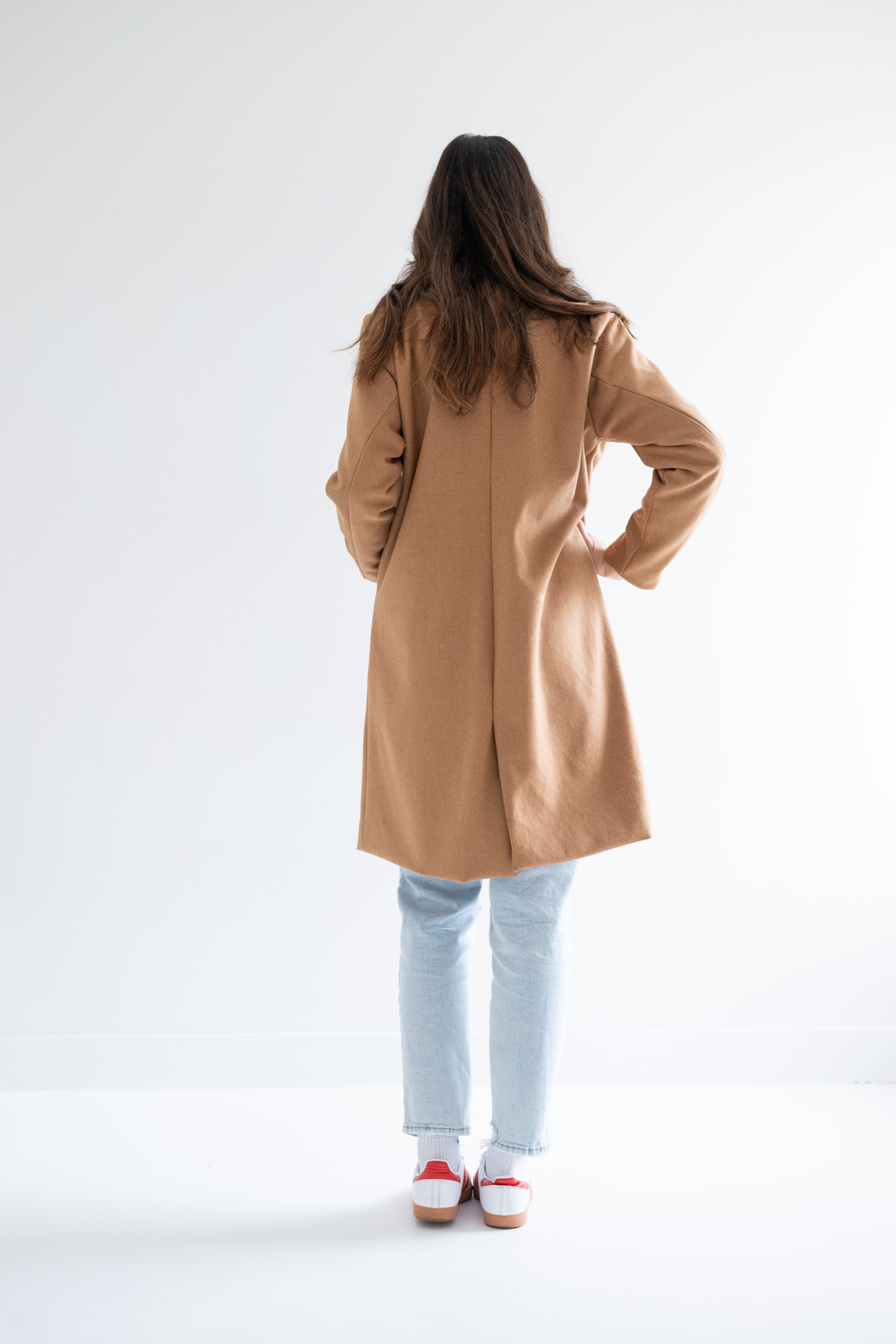 back view of camel wool coat with denim and sneakers