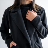 close up of front Black wool coat with one button. Wide collar knee length. Made in canada.