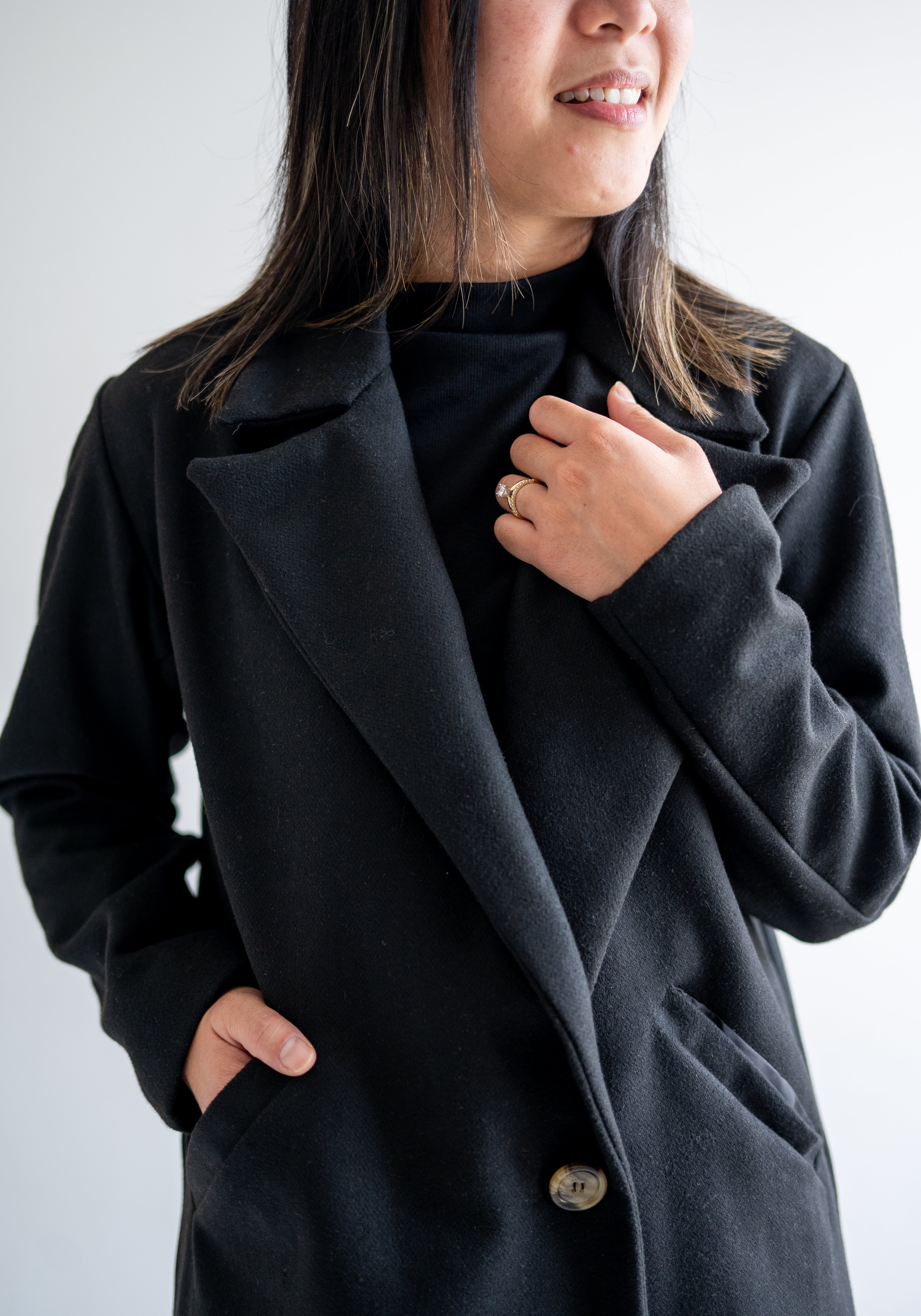 close up of front Black wool coat with one button. Wide collar knee length. Made in canada.