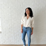 woman wearing cream v-neck sweater and jeans with sneakers