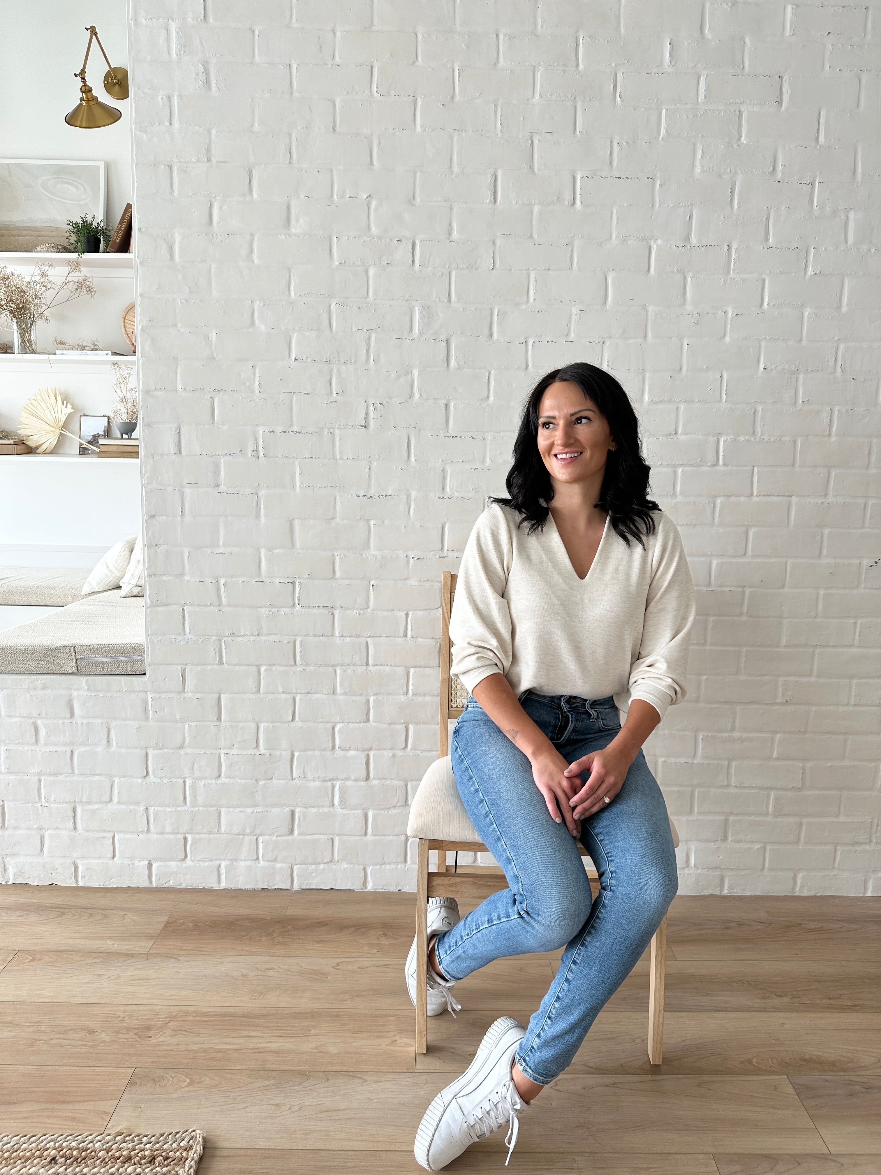 woman sitting wearing cream v-neck sweater made in canada